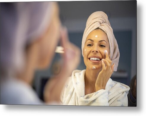 Skin Metal Print featuring the photograph Young woman applying face cream. #1 by Nikola Ilic