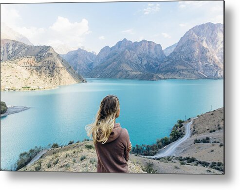 People Metal Print featuring the photograph Young woman looks out across mountain lake #1 by Andrii Lutsyk/ Ascent Xmedia