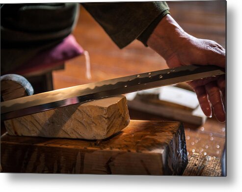 People Metal Print featuring the photograph A craftsmen sharpens a traditional Japanese sword by Trevor Williams