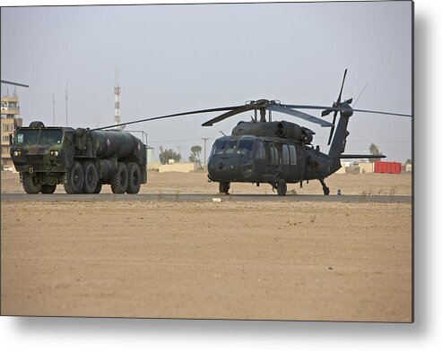 Military Base Metal Print featuring the photograph A U.S. Army UH-60 Black Hawk helicopter with its refueler truck at COB Speicher, Tikrit, Iraq. by Terry Moore/Stocktrek Images