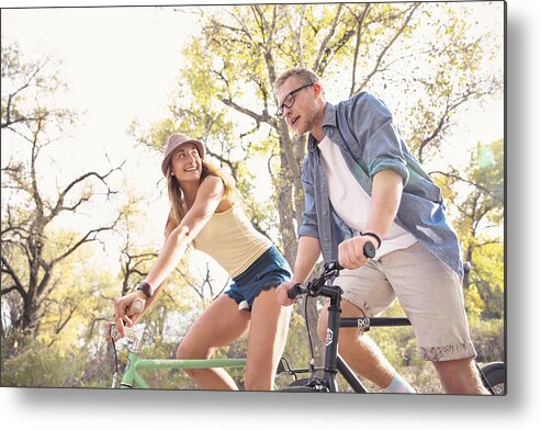 Young Men Metal Print featuring the photograph A young, happy man and woman riding bicycles in a park for fitness by Robb Reece