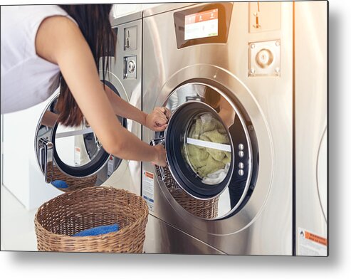 Washing Machine Metal Print featuring the photograph At a laundromat shop with many automatic washing machines, a beautiful woman wearing a mask is doing laundry. by Tongpatong