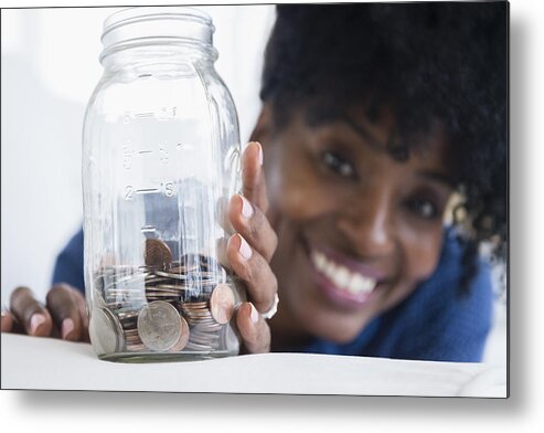 Coin Metal Print featuring the photograph Black woman saving coins in jar by JGI/Jamie Grill