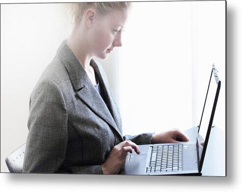 Working Metal Print featuring the photograph Businesswoman working on laptop by Sigrid Gombert