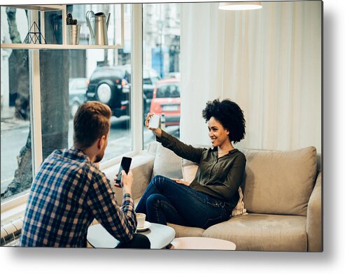 Young Men Metal Print featuring the photograph Couple in coffee shop, woman making selfie by RgStudio