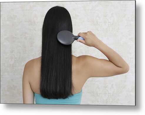 Asian And Indian Ethnicities Metal Print featuring the photograph Dark-haired woman brushing her hair, rear view by Sarah Kastner / STOCK4B-RF