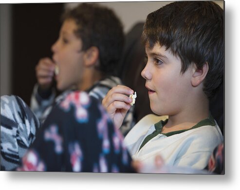 Three Quarter Length Metal Print featuring the photograph Hispanic boys eating popcorn and watching television by GM Visuals