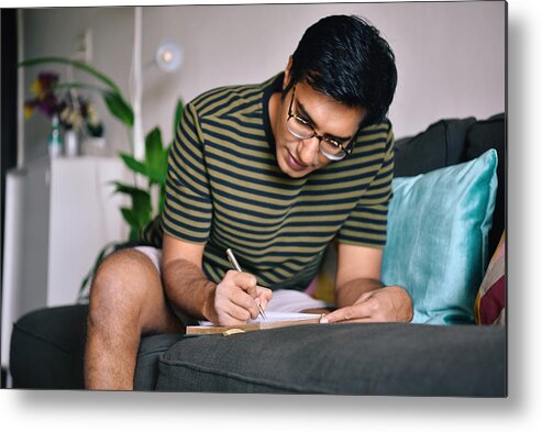 Mental Health Metal Print featuring the photograph Man writing in a diary sitting on a sofa by Mayur Kakade