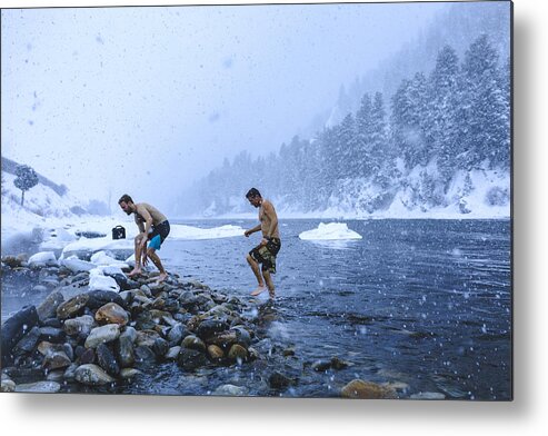 Young Men Metal Print featuring the photograph Men walking on stones in river during snowfall by Cavan Images