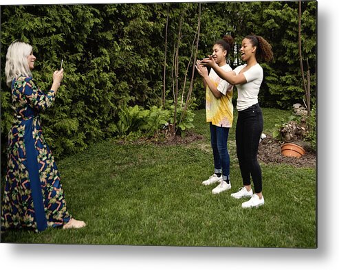 Diversity Metal Print featuring the photograph Mixed-race sisters being filmed by mother in backyard. by Martinedoucet