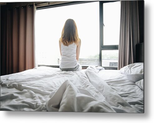 Problems Metal Print featuring the photograph Portrait of depressed woman sitting alone on bed, looking to outside the window. by Boy_Anupong