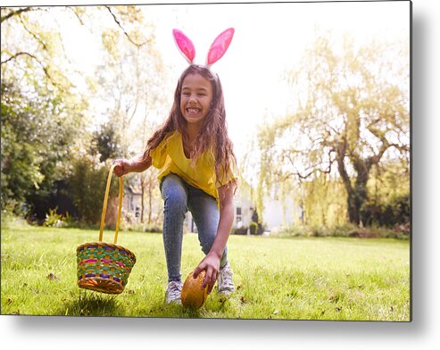 Easter Metal Print featuring the photograph Portrait Of Girl Wearing Bunny Ears Finding Chocolate Egg On Easter Egg Hunt In Garden by Monkeybusinessimages