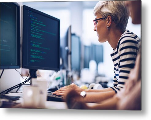 Working Metal Print featuring the photograph Profile view of young female programmer working on computer software in the office. by Skynesher