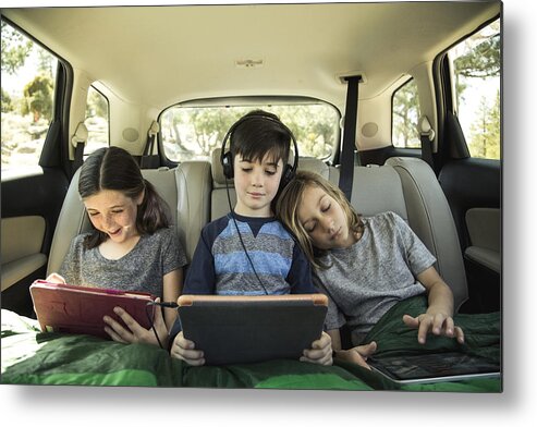 California Metal Print featuring the photograph Siblings using digital tablet in back seat of car on road trip by The Good Brigade