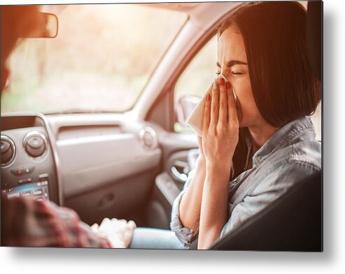 White People Metal Print featuring the photograph Sick girl is sneezing in napkin. She has closed her eyes. It is paiful for her to do it. Guy is holding his hand on her leg. by Estradaanton