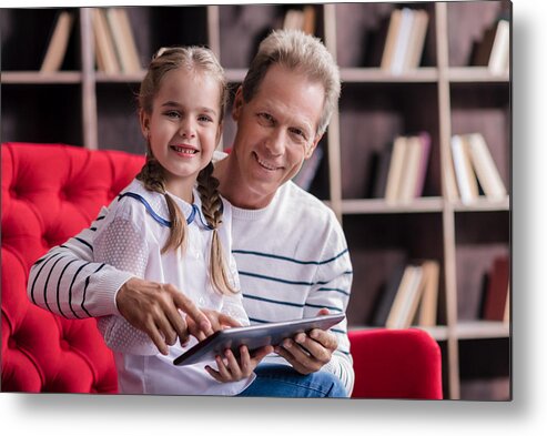 Child Metal Print featuring the photograph Smiling girl resting with her grandfather and holding the tablet by Yacobchuk
