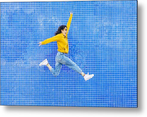 Skin Metal Print featuring the photograph Woman jumping in front of a blue background by Karrastock