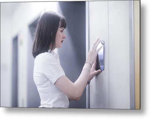 People Metal Print featuring the photograph Woman using wall mounted touch screen control panel by Sigrid Gombert