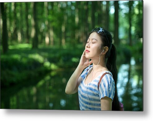 Expertise Metal Print featuring the photograph Young asian woman listening to music in forest,with eyes closed by Xia Yuan