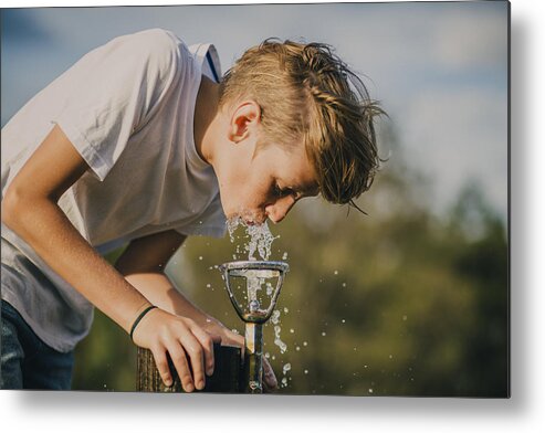 Young Men Metal Print featuring the photograph Young Boy Drinking from a Water Fountain by SolStock