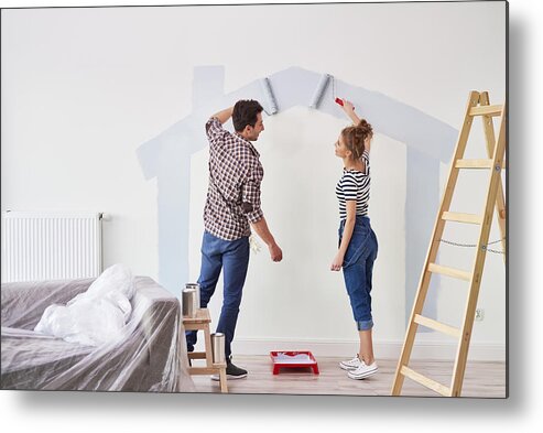 Working Metal Print featuring the photograph Young couple painting the interior wall in their new apartment by Gpointstudio