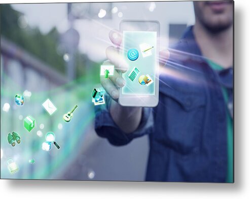 People Metal Print featuring the photograph Young man holding up smartphone with apps and icons coming out of it by Innocenti