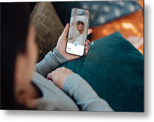 People Metal Print featuring the photograph Young mother using baby monitor app on her smart phone while sitting in the living room by Oscar Wong