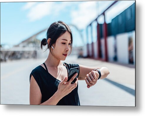 Internet Metal Print featuring the photograph Young woman using smartwatch and doing outdoor workout in the city by Oscar Wong