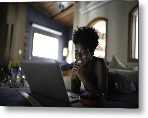 Internet Metal Print featuring the photograph Young women watching movie on a laptop at home by FG Trade