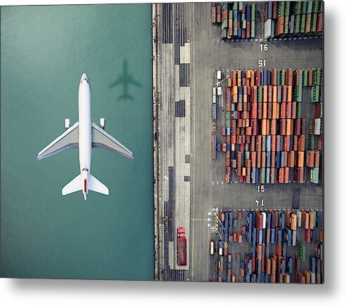 Working Metal Print featuring the photograph Airplane flying over container port by Orbon Alija