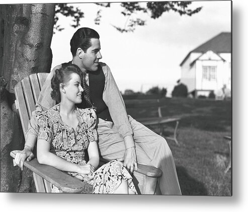 Heterosexual Couple Metal Print featuring the photograph Couple Relaxing On Deckchair In Garden by George Marks