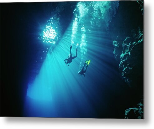 Underwater Metal Print featuring the photograph Two Divers Swim Thru Sunbeams In Sea by Kim Westerskov