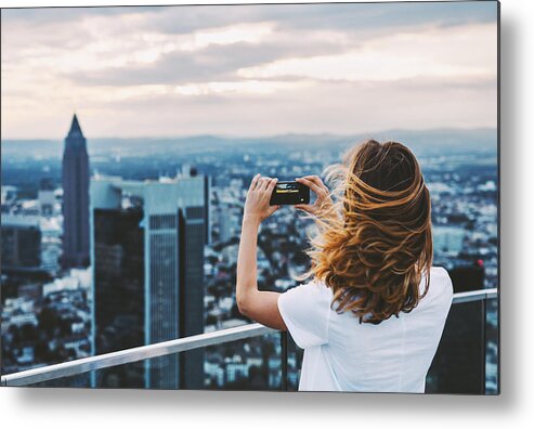 Wind Metal Print featuring the photograph Woman taking photo with mobile phone above city #1 by Xsandra
