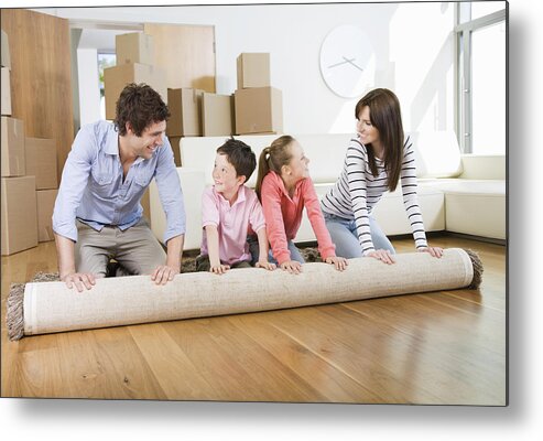 Young Men Metal Print featuring the photograph Family unrolling carpet together in new home by Robert Daly