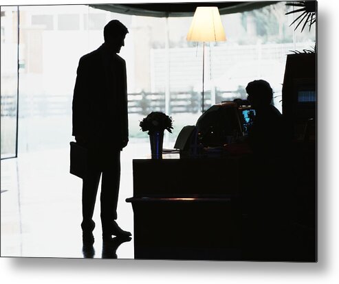 Working Metal Print featuring the photograph Silhouette of businessman standing in front of desk by Eric Audras