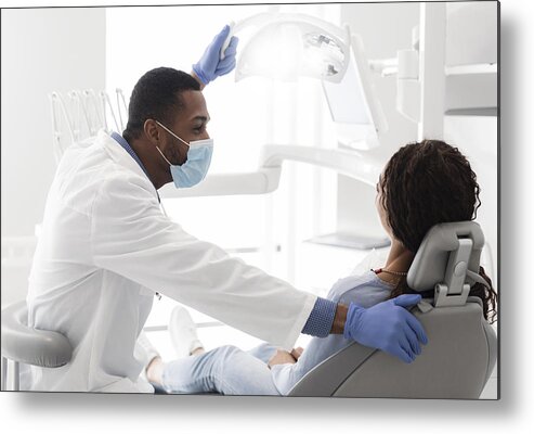 People Metal Print featuring the photograph Young black stomatologist talking to his female patient by Prostock-Studio