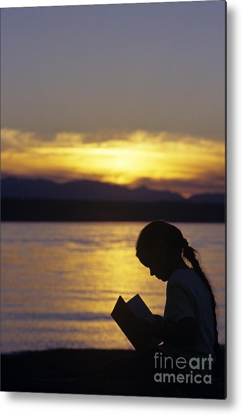 Travel Metal Print featuring the photograph Young girl silhouetted reading a book on the beach at sunset by Jim Corwin