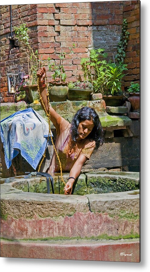 Well Metal Print featuring the photograph A woman draws water at a well in Bhaktapur Nepal by Christopher Byrd