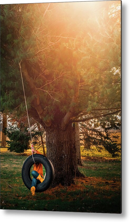 Tire Swing Metal Print featuring the photograph Boy Swinging In Tire Swing Under The Tree During Sunset by Cavan Images