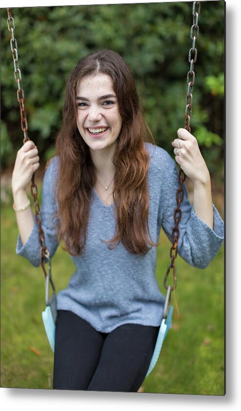 Girl Metal Print featuring the photograph Pretty Teen Girl Sitting On Swing Smiling With Greenery In Background by Cavan Images
