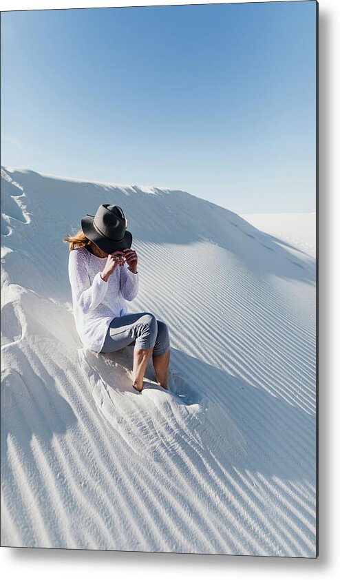 Woman Metal Print featuring the photograph Woman Wearing Hat Sitting On Desert At White Sands National Monument During Sunny Day by Cavan Images