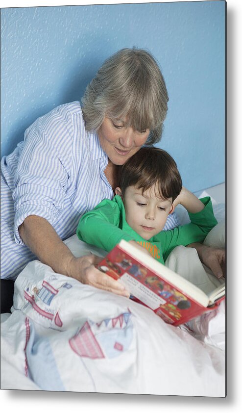 Child Metal Print featuring the photograph Grandmother and grandson reading book in bed by Compassionate Eye Foundation/Natasha Alipour Faridani