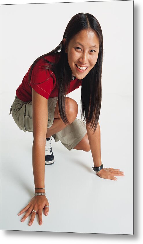 White Background Metal Print featuring the photograph Young Woman With Long Hair Wears Red T-shirt And Shorts Crouches Her Hands On Floor Smiles To Camera by Photodisc