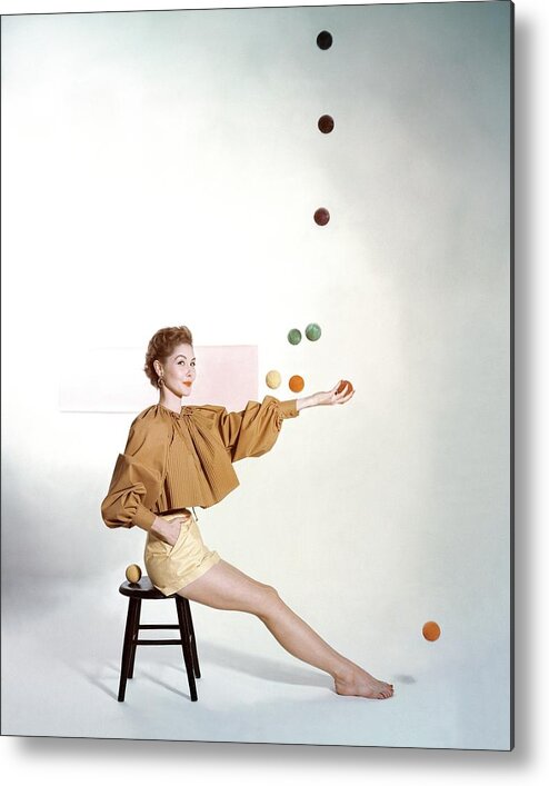Juggling Metal Print featuring the photograph A Model Sitting On A Stool Juggling by John Rawlings
