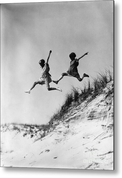 1920s Metal Print featuring the photograph Two Girls Leaping Off Sand Dune by H Armstrong Roberts and ClassicStock