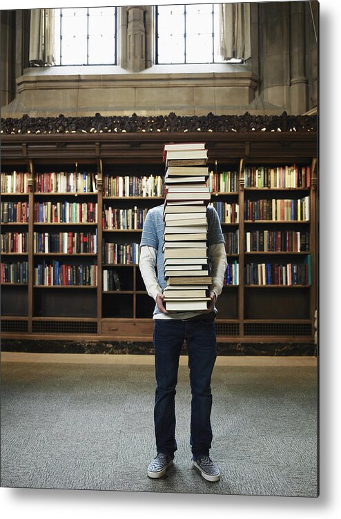 Education Metal Print featuring the photograph Young man carrying stack of books in university library by Thomas Barwick