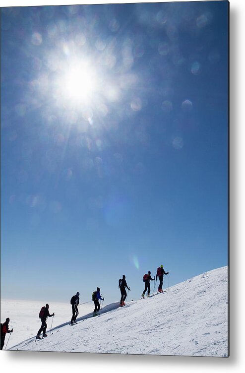 Following Metal Print featuring the photograph Skiers Ascending An Alpine Slope by Buena Vista Images