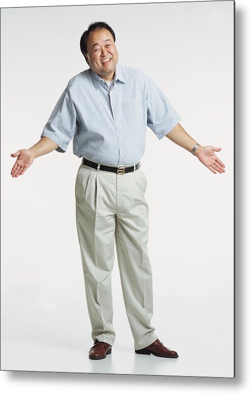 Human Arm Metal Print featuring the photograph Handsome Middle Aged Asian Adult Male Wearing A Light Blue Short Sleeved Shirt And Cream Colored Slacks Stands With Shrugged Shoulders And Hands In The Air As He Looks At The Camera With A Anxious Smile by Photodisc