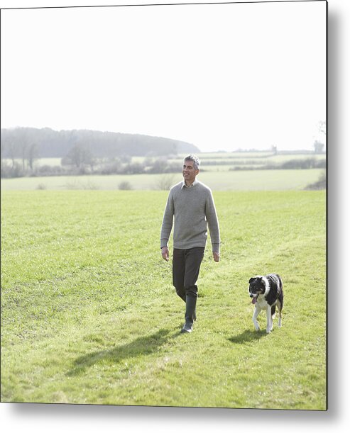 Pets Metal Print featuring the photograph Man walking in countryside with pet dog by Dougal Waters