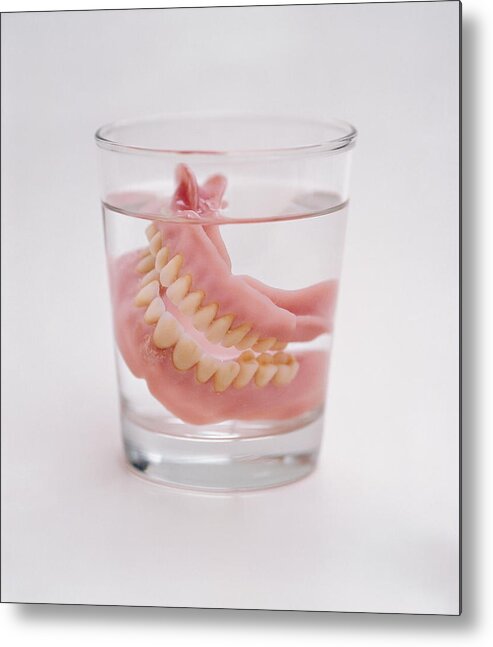 White Background Metal Print featuring the photograph False teeth in glass of water, close-up by Christian Adams